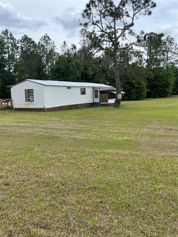 A white mobile home sits on a large grassy lot near a tall pine tree — 12482 161ST ROAD, LIVE OAK, FL