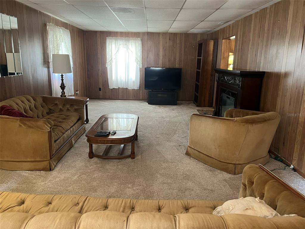 A living room features wood-paneled walls, a drop ceiling, carpeted floors, and vintage furniture — 12482 161ST ROAD, LIVE OAK, FL