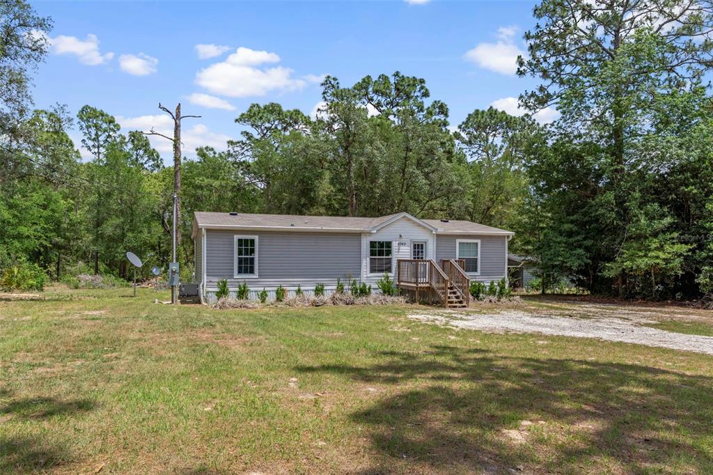 A single-story manufactured home with gray siding sits on a grassy lot with trees — 2063 S SUNWOOD POINT, HOMOSASSA, FL