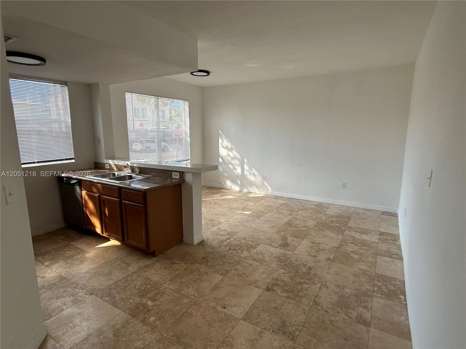 A kitchen with wood cabinets and a breakfast bar opens into an empty living area — 953 SW 10th St # 3, Miami FL 33130, MIAMI, FL