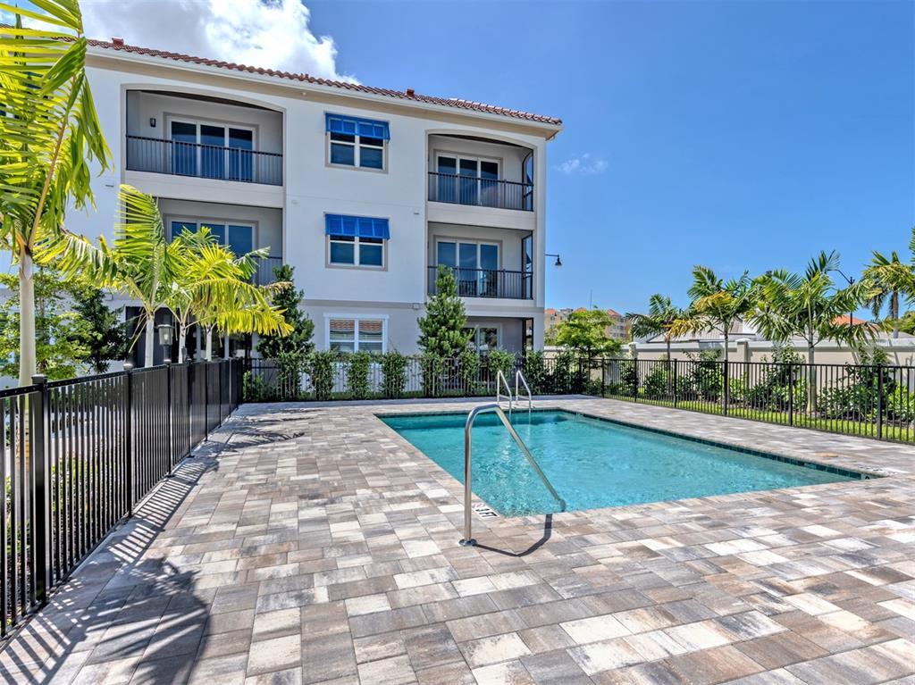 A swimming pool with a metal handrail sits on a paved patio beside an apartment building — 787 S. TAMIAMI TRAIL UNIT 301, VENICE, FL