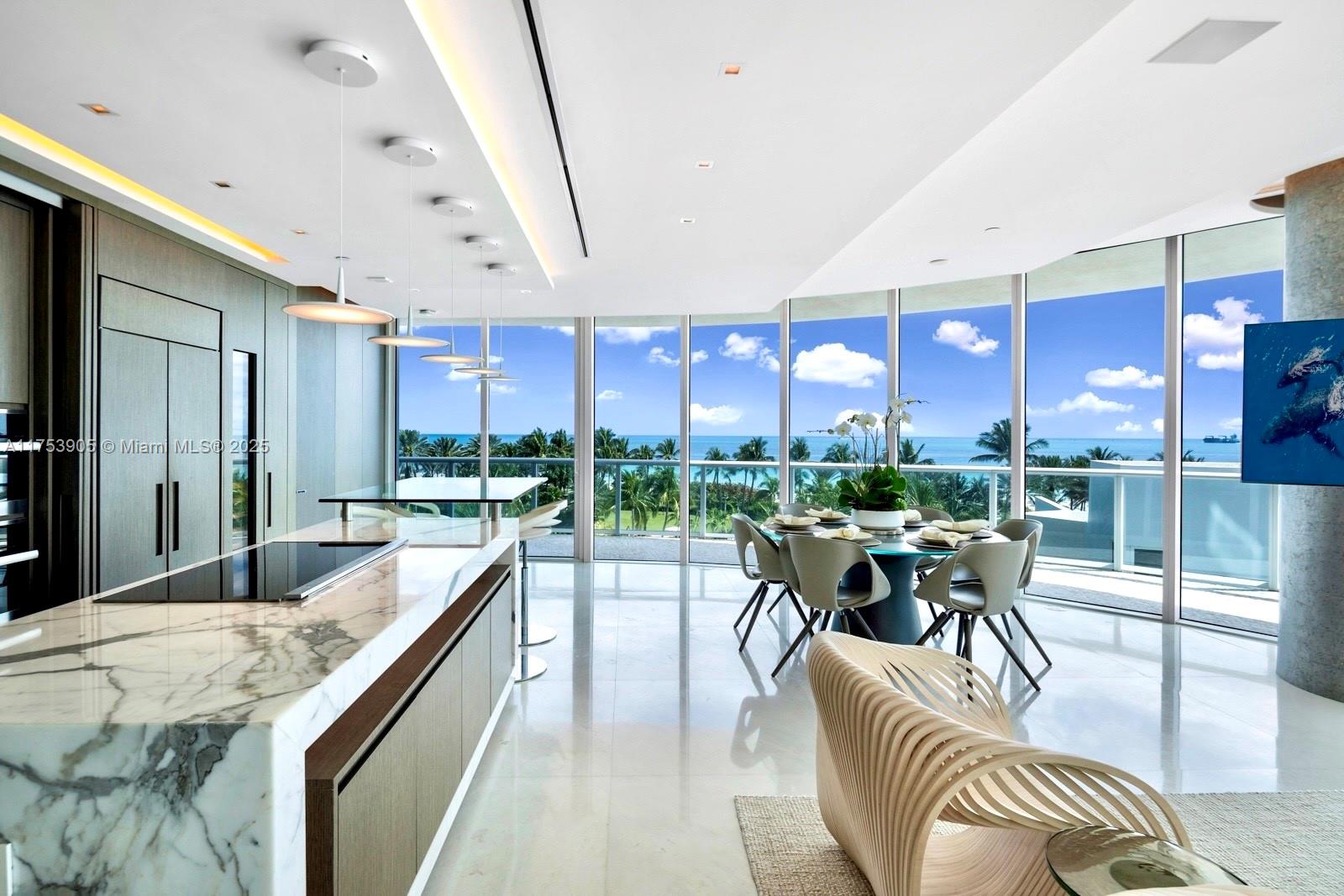 A modern kitchen and dining area feature marble countertops, floor-to-ceiling windows, and ocean views — 100 S Pointe Dr # 606, Miami Beach FL 33139, MIAMI BEACH, FL
