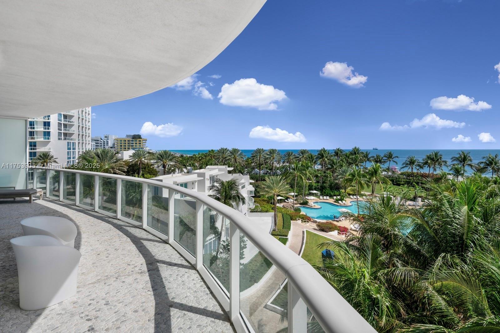 A curved balcony with white chairs overlooks a swimming pool, palm trees, and the ocean — 100 S Pointe Dr # 606, Miami Beach FL 33139, MIAMI BEACH, FL
