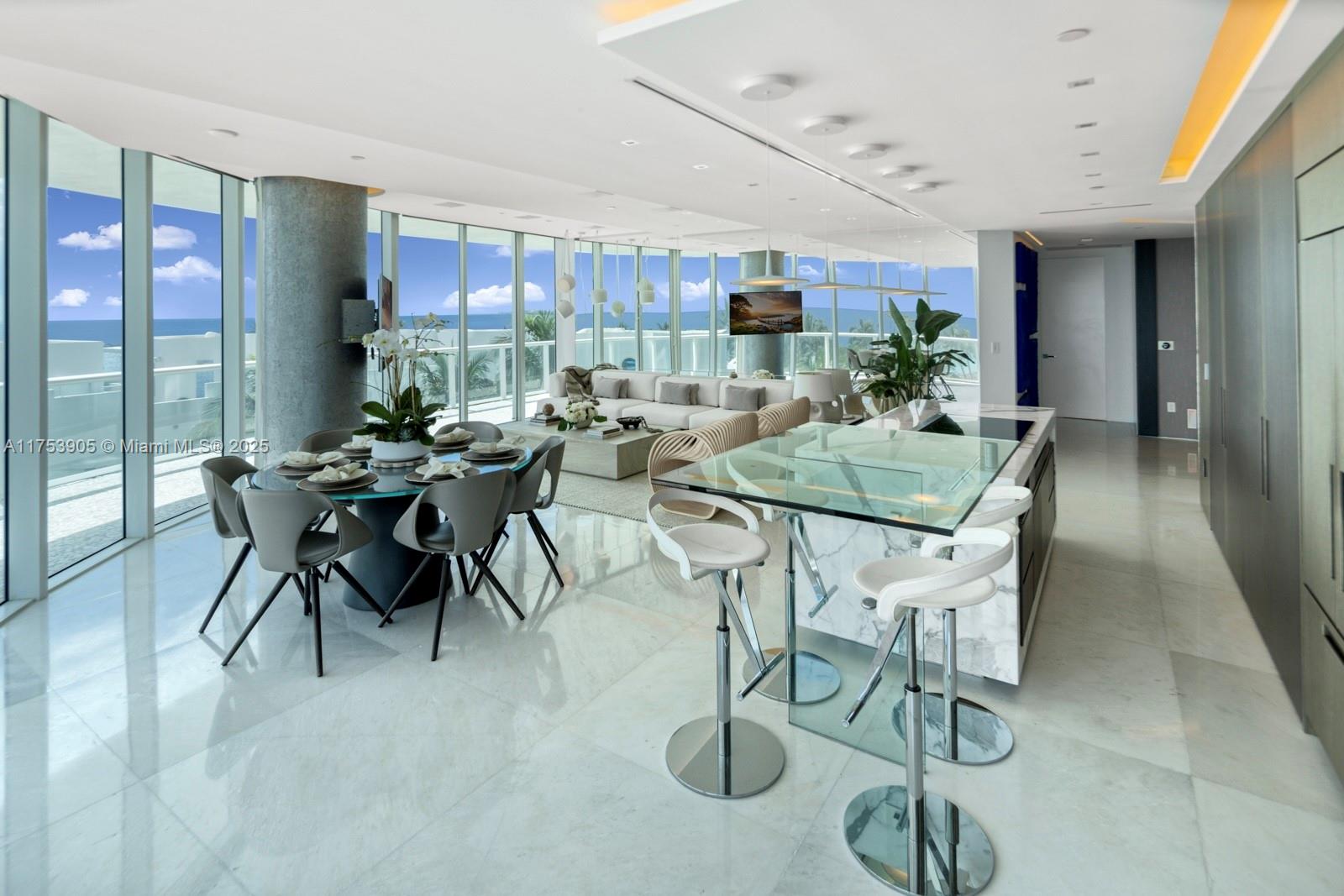 An open-concept living and dining area features floor-to-ceiling windows, marble flooring, and a kitchen island — 100 S Pointe Dr # 606, Miami Beach FL 33139, MIAMI BEACH, FL