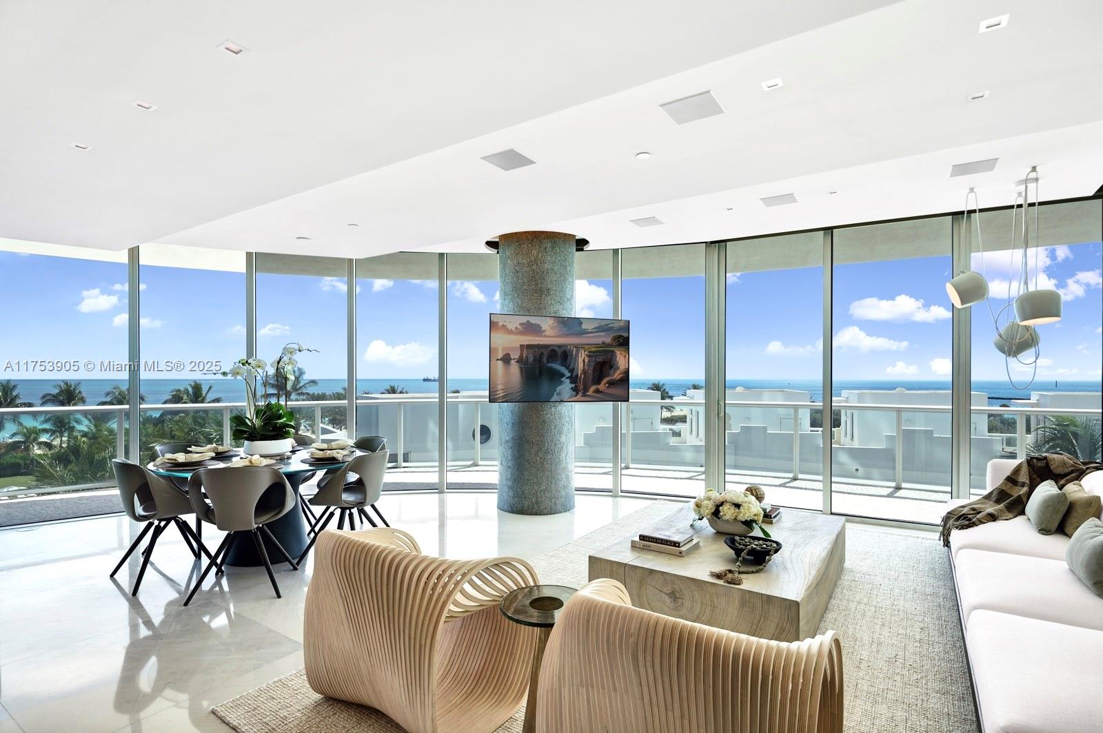 A modern living and dining area features floor-to-ceiling windows with ocean views and a central column — 100 S Pointe Dr # 606, Miami Beach FL 33139, MIAMI BEACH, FL