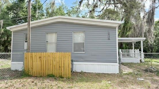 A gray mobile home with a wooden fence and a small covered porch — 10920-10928 MALATI STREET, NEW PORT RICHEY, FL
