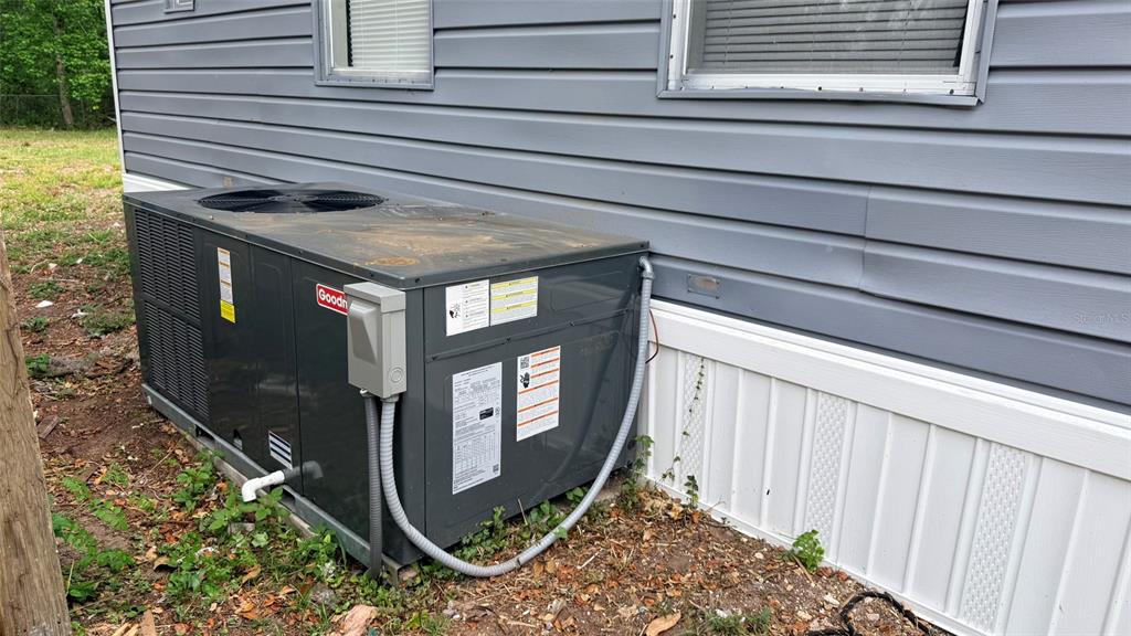A Goodman HVAC unit sits on the ground next to the gray siding of a house — 10920-10928 MALATI STREET, NEW PORT RICHEY, FL