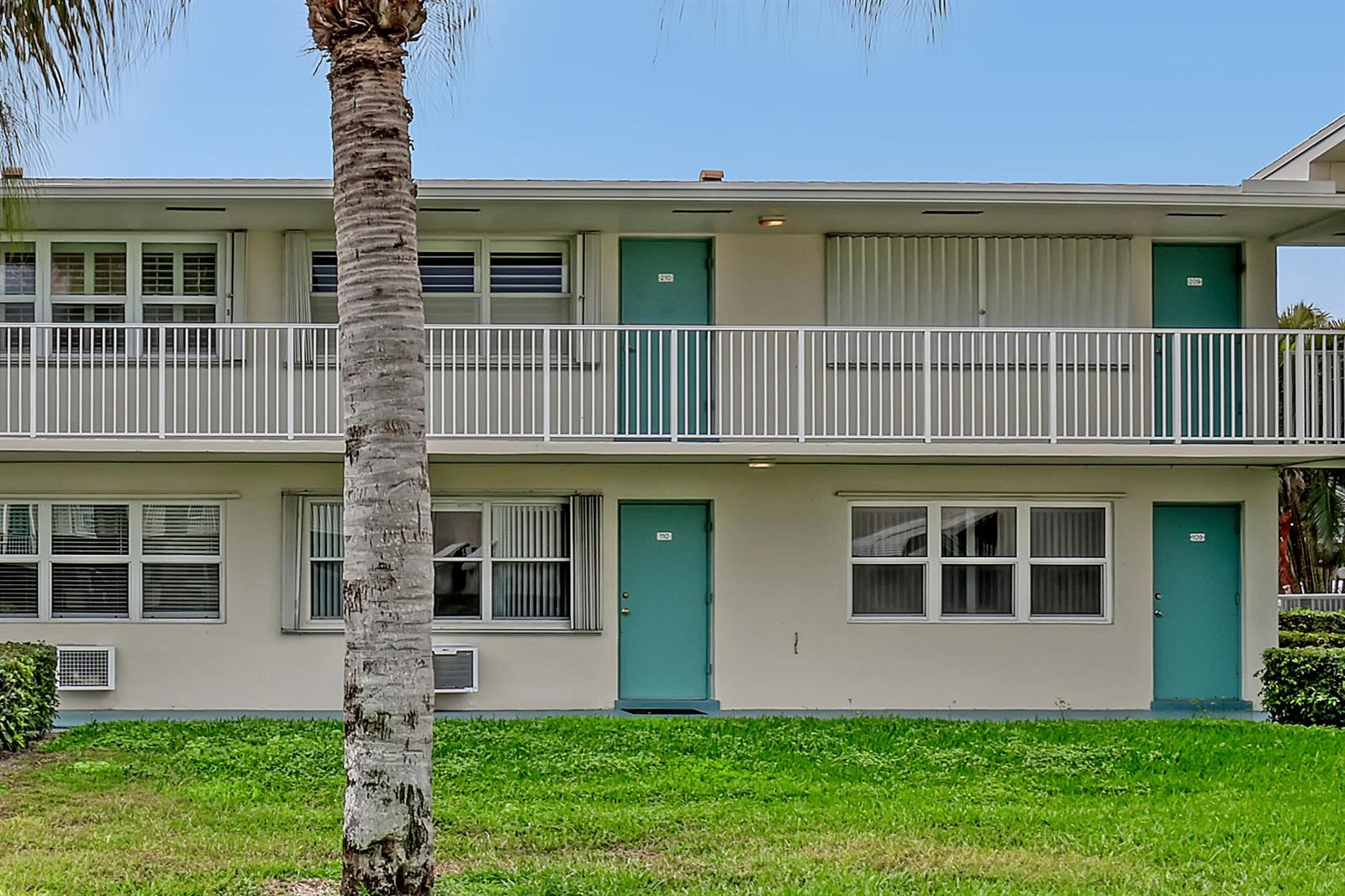 A two-story apartment building exterior features teal doors, white railings, and a grassy lawn — 680 Horizon W # 110, Boynton Beach FL 33435, BOYNTON BEACH, FL