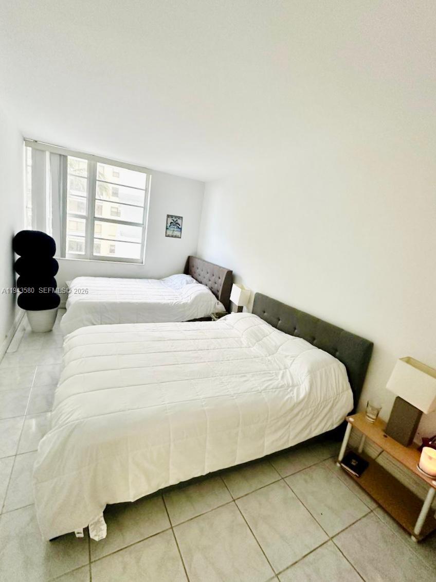 A bedroom features two beds with white bedding, tiled floors, and a large window — 100 Lincoln Rd # 524, Miami Beach FL 33139, MIAMI BEACH, FL