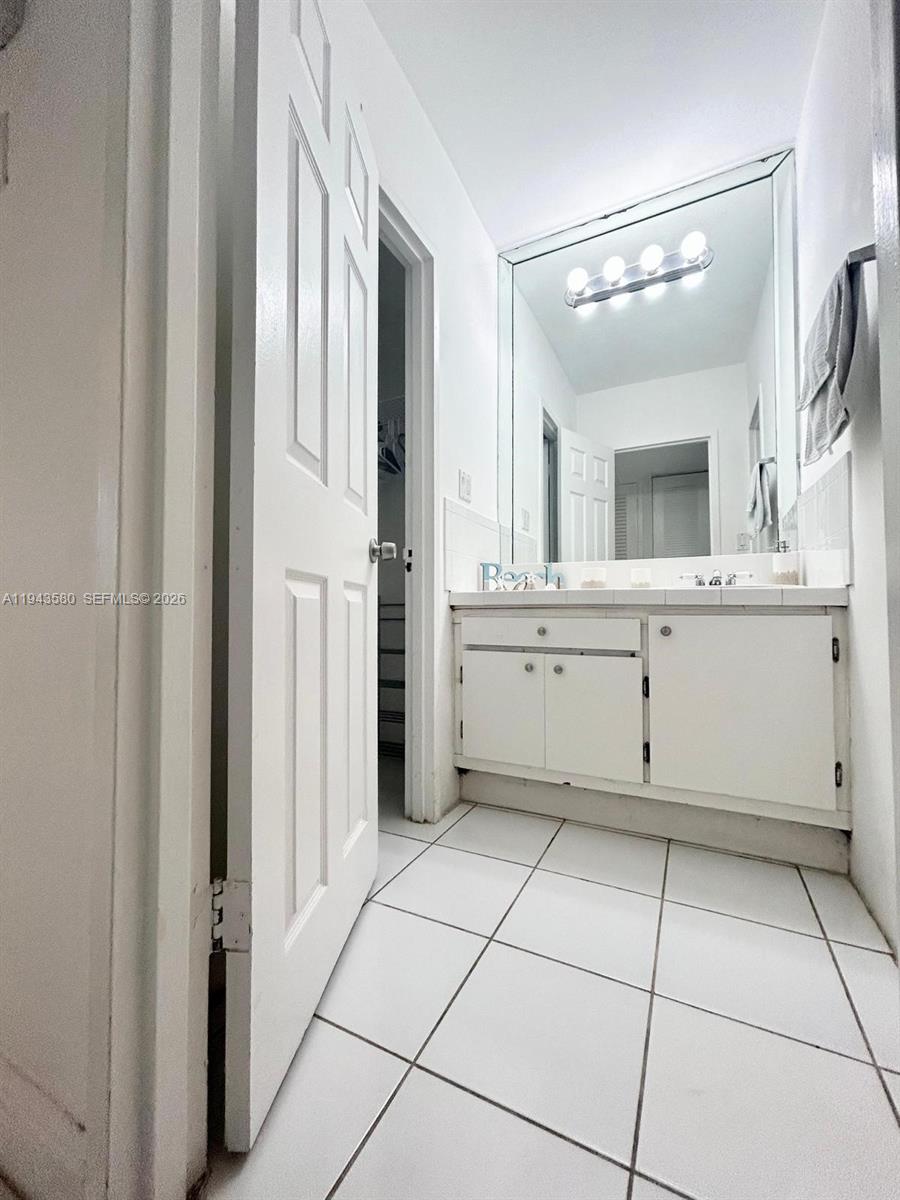 A bathroom features white cabinets, a large mirror, and white tile flooring — 100 Lincoln Rd # 524, Miami Beach FL 33139, MIAMI BEACH, FL