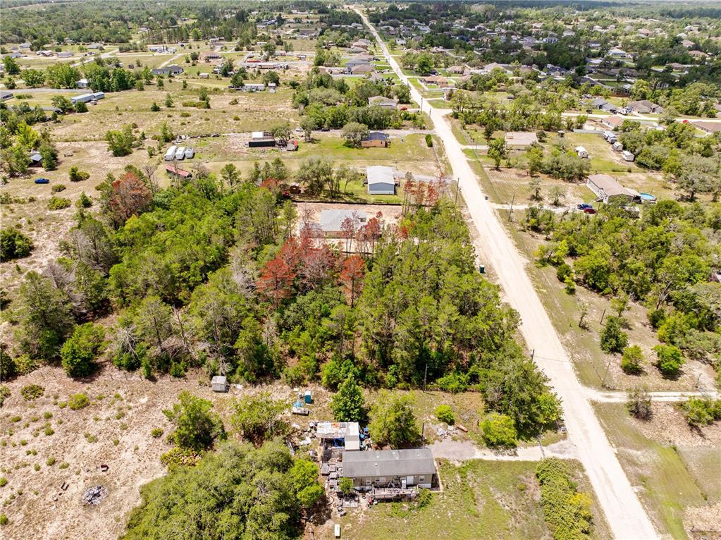 An aerial view shows a rural residential property with a house, trees, and dirt roads — 0 FULMAR ROAD, WEEKI WACHEE, FL