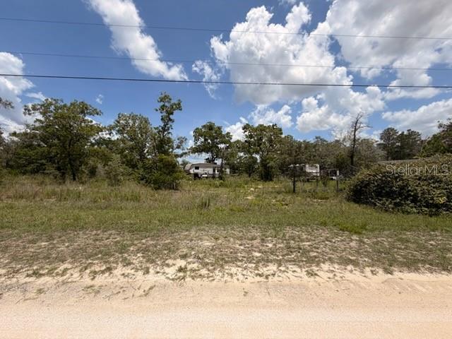 A vacant, grassy lot with scattered trees and a small trailer in the background — 0 FULMAR ROAD, WEEKI WACHEE, FL