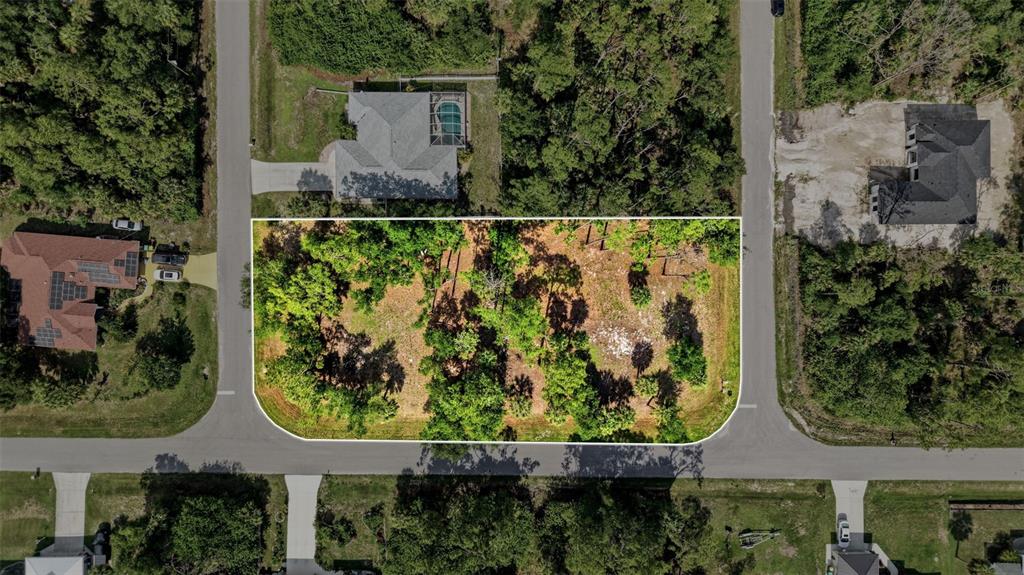 An aerial view shows a vacant, wooded residential lot outlined in white between two streets — 1096 & 1112 CABOT STREET, PORT CHARLOTTE, FL