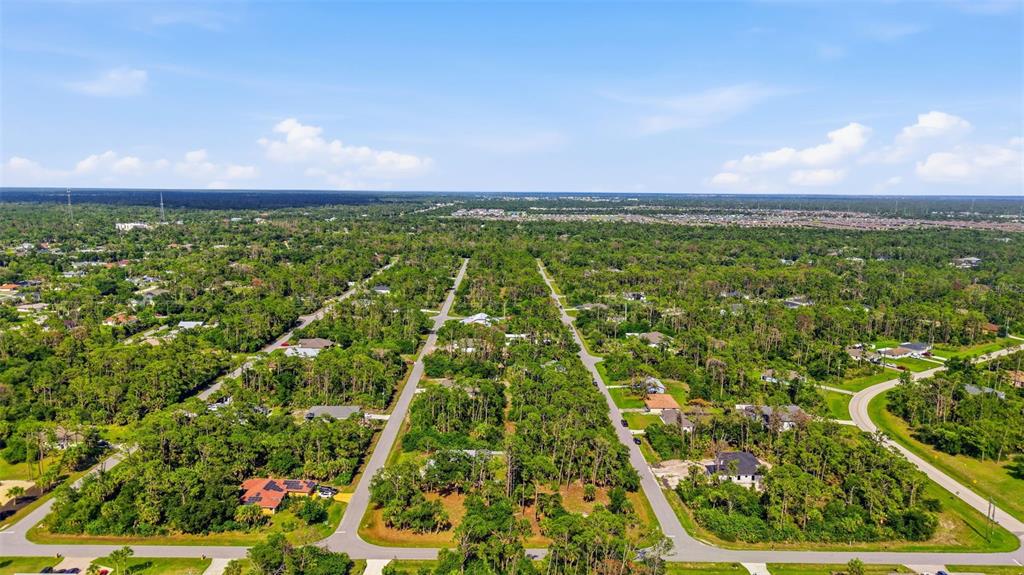 An aerial view shows a residential neighborhood with scattered houses surrounded by dense trees — 1096 & 1112 CABOT STREET, PORT CHARLOTTE, FL