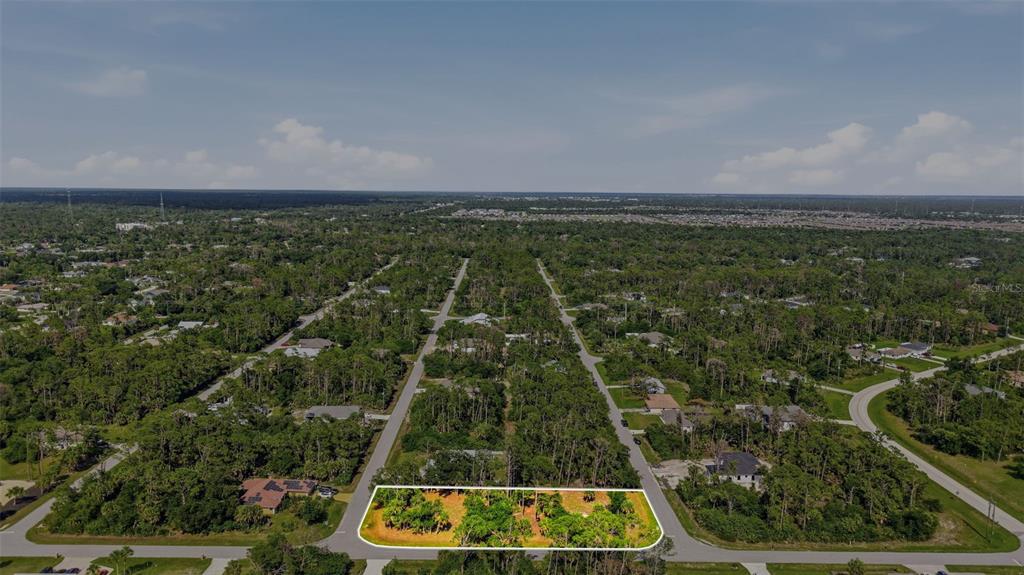 An aerial view shows a vacant, wooded residential lot outlined in white within a suburban neighborhood — 1096 & 1112 CABOT STREET, PORT CHARLOTTE, FL