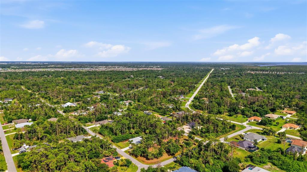 An aerial view shows a suburban neighborhood with houses scattered among dense green trees — 1096 & 1112 CABOT STREET, PORT CHARLOTTE, FL