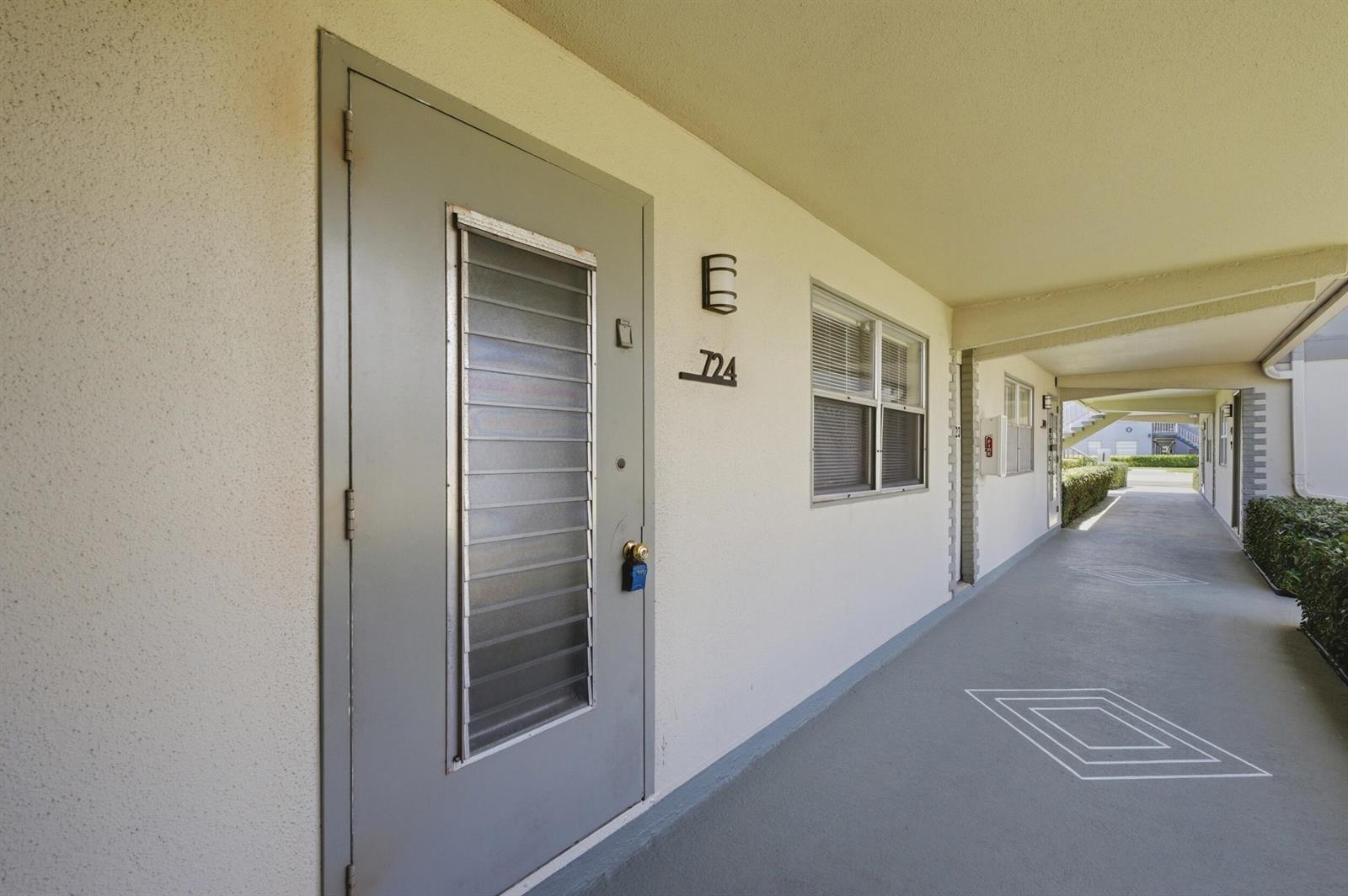 An exterior view of an apartment entrance with a gray door and a numbered sign — 724 Flanders P, Delray Beach FL 33484, DELRAY BEACH, FL