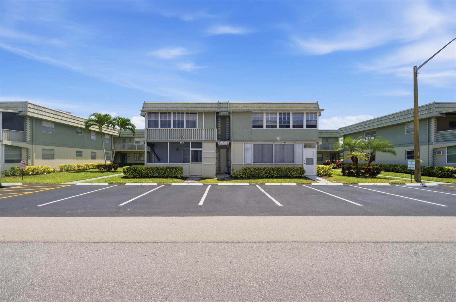 A two-story apartment building with a parking lot in the foreground under a blue sky — 724 Flanders P, Delray Beach FL 33484, DELRAY BEACH, FL