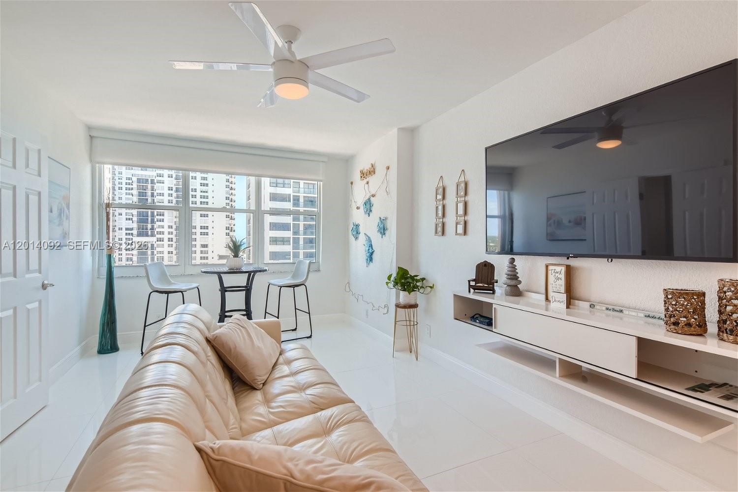 A bright living room features a white sofa, a wall-mounted television, and a dining nook — 2501 S Ocean Dr # 1103, Hollywood FL 33019, HOLLYWOOD, FL