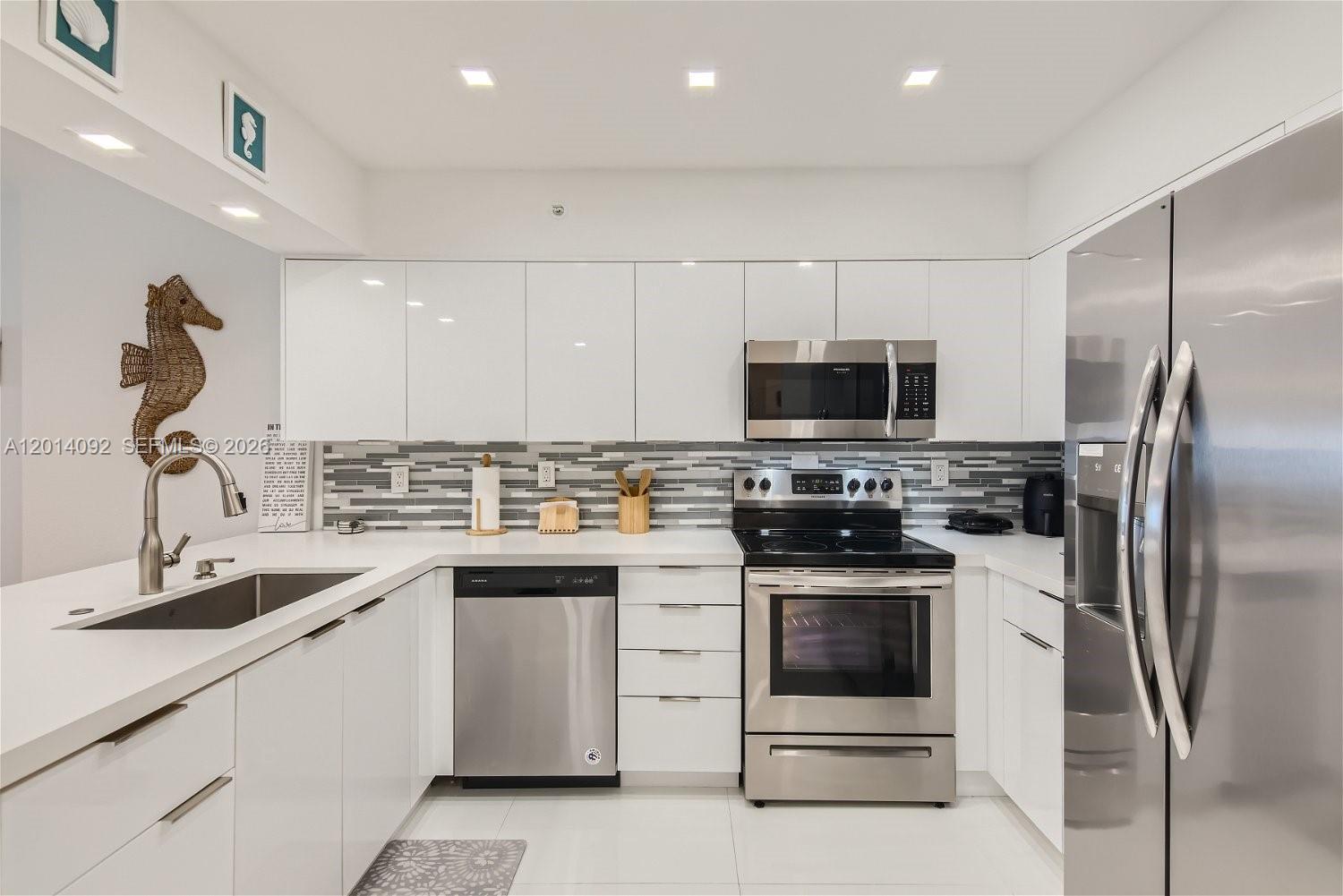 A modern kitchen features white cabinets, stainless steel appliances, and a gray tiled backsplash — 2501 S Ocean Dr # 1103, Hollywood FL 33019, HOLLYWOOD, FL