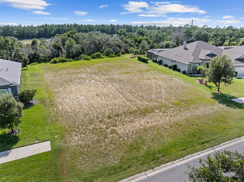 An elevated view of a vacant, grassy residential lot situated between two existing houses — 3040 ACOMA DRIVE, ORMOND BEACH, FL