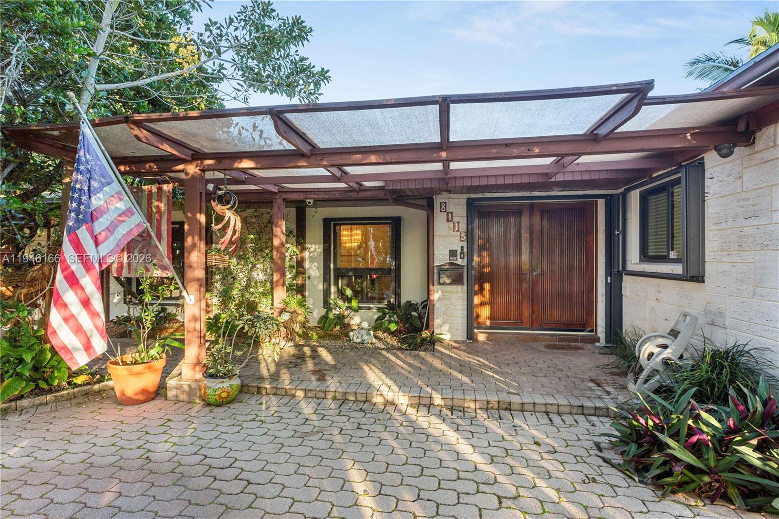 A paved driveway leads to a covered entryway with a wooden pergola and double doors — 8115 SW 92nd Ct, Miami FL 33173, MIAMI, FL