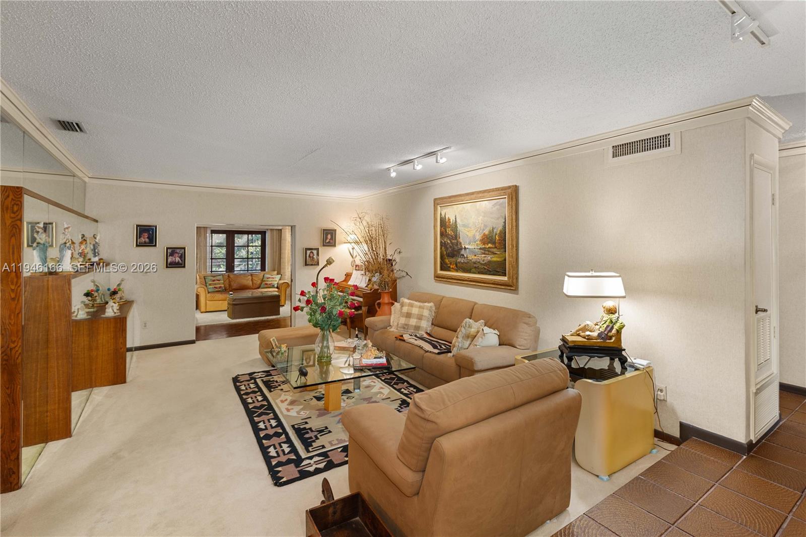 A living room features beige carpeting, tan sofas, a glass coffee table, and wall art — 8115 SW 92nd Ct, Miami FL 33173, MIAMI, FL