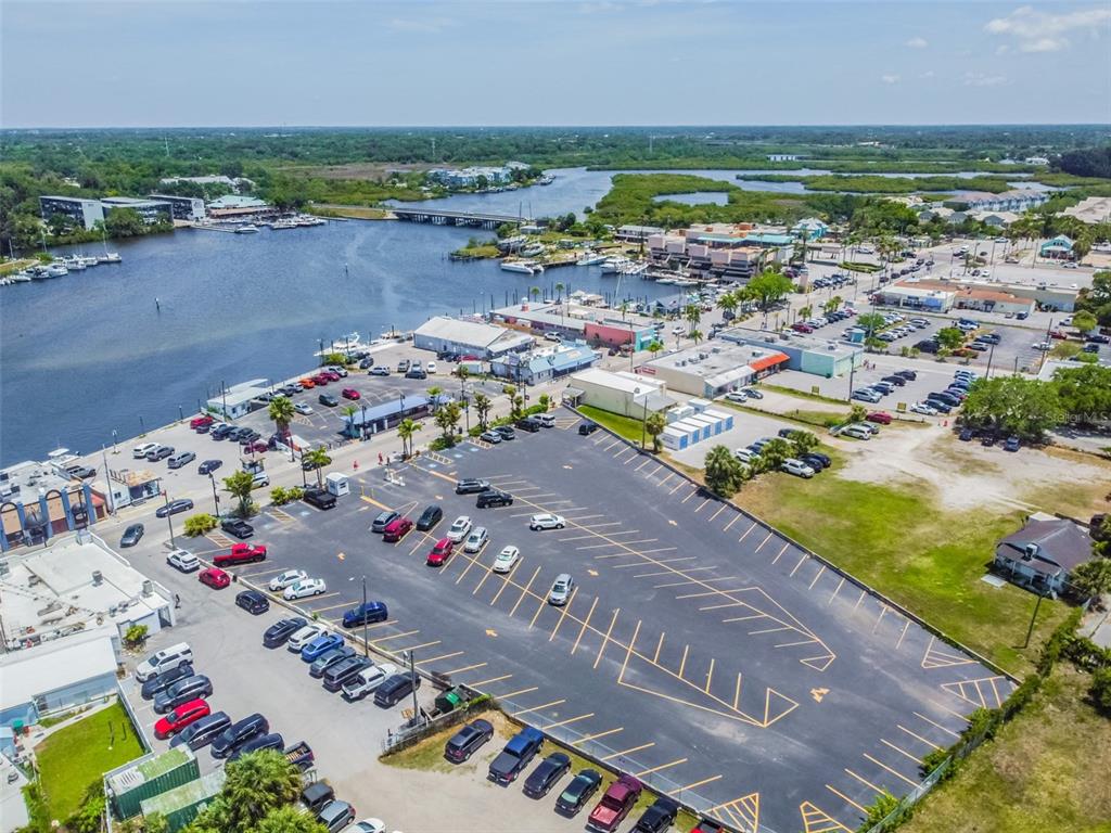 An aerial view shows a waterfront parking lot, commercial buildings, and a bridge over water — 00 ATHENS, TARPON SPRINGS, FL