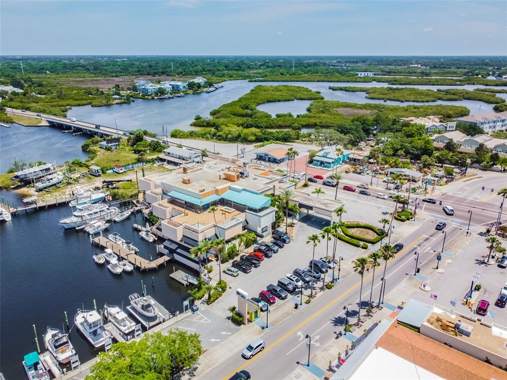 An aerial view shows a waterfront building with a marina, parking lot, and nearby bridge — 00 ATHENS, TARPON SPRINGS, FL
