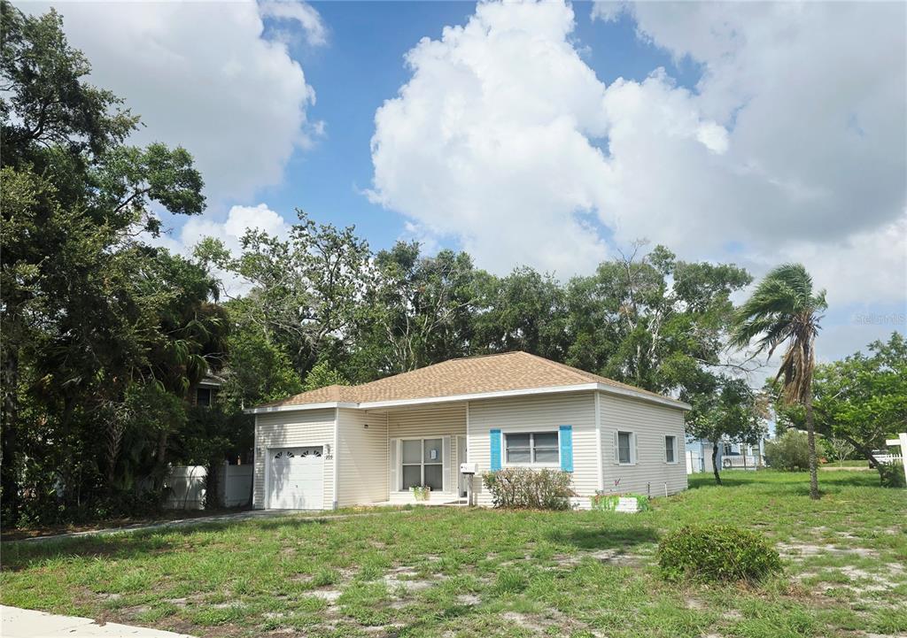 A single-story beige house with a garage and blue shutters sits on a grassy lot — 205 N MISSOURI AVENUE, CLEARWATER, FL