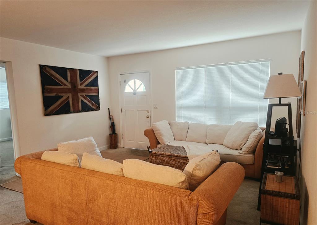A living room features an orange sofa, a white sofa, and a Union Jack wall art — 205 N MISSOURI AVENUE, CLEARWATER, FL