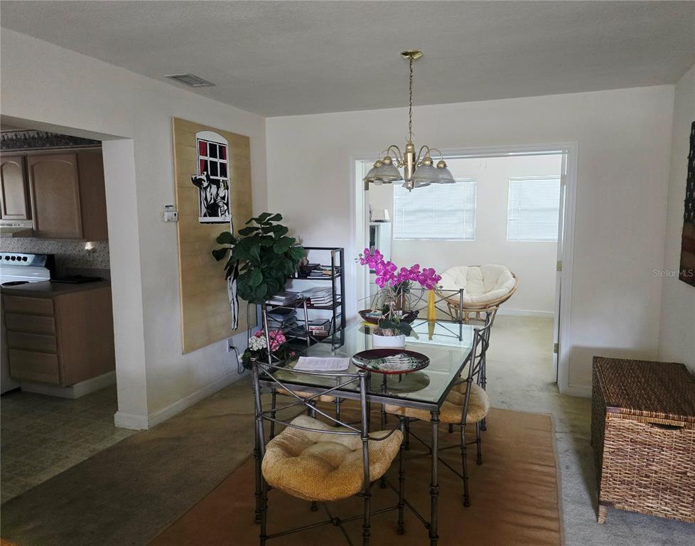A dining room features a glass-topped table, metal chairs, and a view into a sunroom — 205 N MISSOURI AVENUE, CLEARWATER, FL