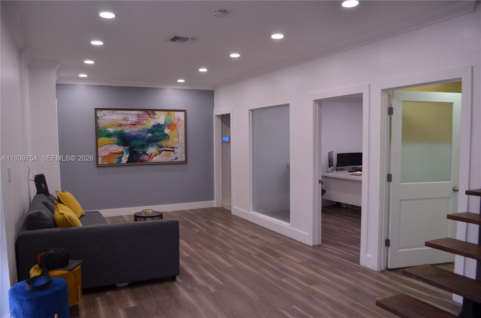 A modern office lounge features a gray sofa, abstract art, and wood-look flooring — 7311 NW 12th St # 20, Miami FL 33126, MIAMI, FL