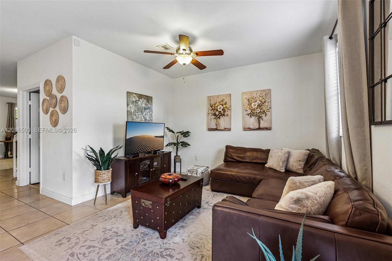 A living room features a brown leather sectional, a wooden coffee table, and a television — 284 SE 37th Ter, Homestead FL 33033, HOMESTEAD, FL