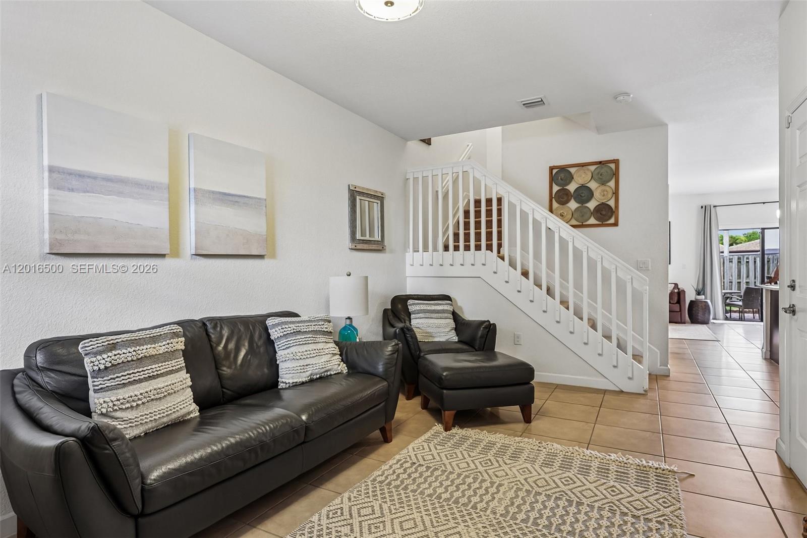 A living room features a dark leather sofa, a matching armchair with ottoman, and a staircase — 284 SE 37th Ter, Homestead FL 33033, HOMESTEAD, FL
