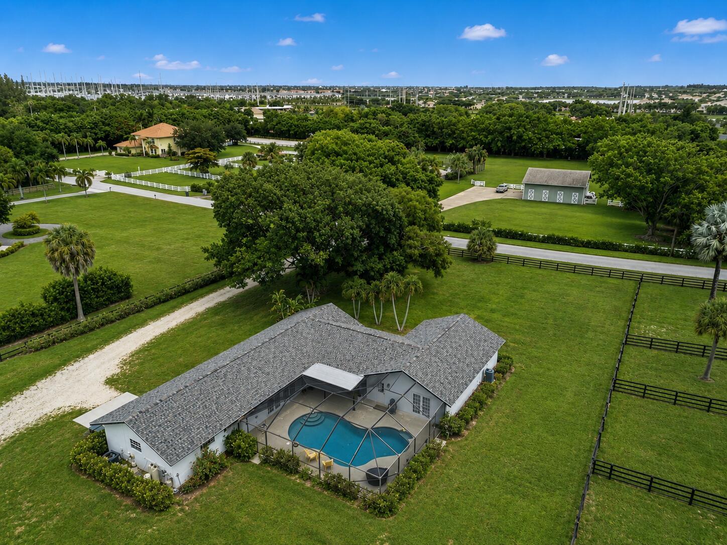 An aerial view of a house with a screened-in pool on a large grassy lot — 785 Cindy Drive, Wellington FL 33414, WELLINGTON, FL