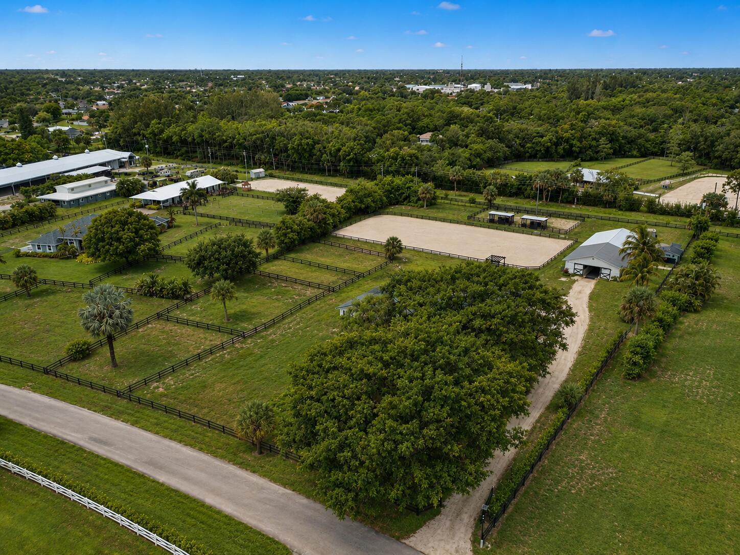 An aerial view of a rural property featuring fenced pastures, a riding arena, and barns — 785 Cindy Drive, Wellington FL 33414, WELLINGTON, FL