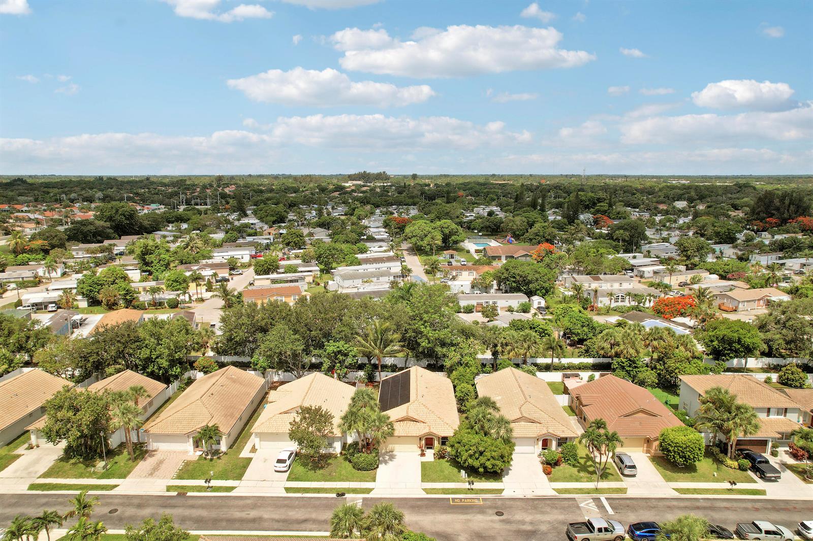 An aerial view shows a suburban neighborhood with single-family homes and lush green trees — 1017 Fosters Mill Road, Boynton Beach FL 33436, BOYNTON BEACH, FL