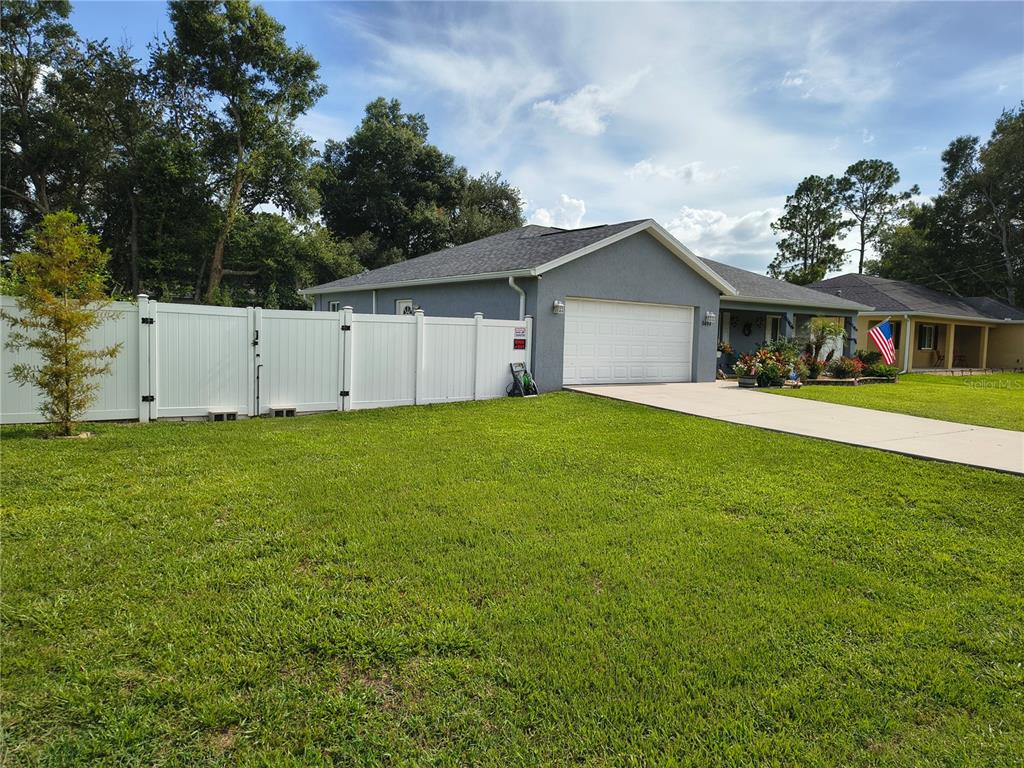 The exterior of a gray house features a covered porch, landscaping, and a stone border — 9444 SE 161ST STREET, SUMMERFIELD, FL