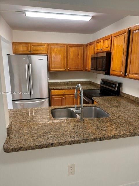 A kitchen features wood cabinets, granite countertops, a stainless steel refrigerator, and a double sink — MIAMI, FL