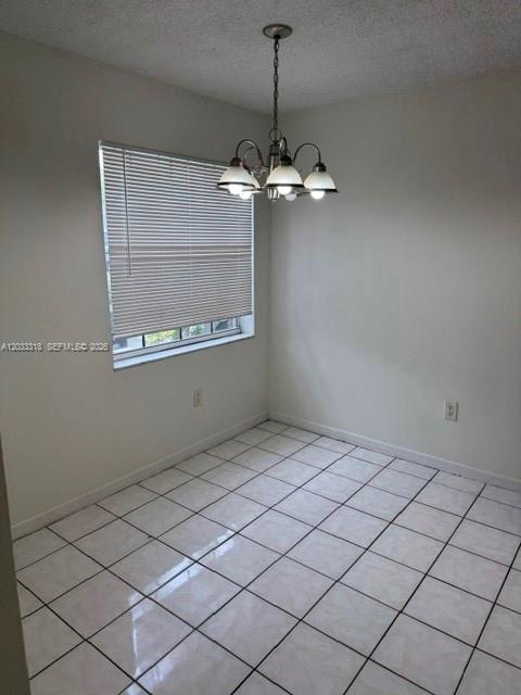 A dining area features white tiled floors, a window with blinds, and a hanging chandelier — MIAMI, FL