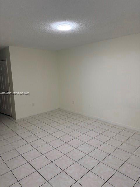 An empty room features white walls, a tiled floor, and a single ceiling light fixture — MIAMI, FL
