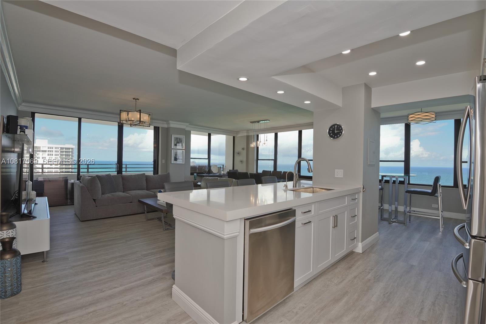 A modern kitchen with a white island and stainless steel appliances overlooks an oceanfront living area — 3505 S Ocean Dr # 12, Hollywood FL 33019, HOLLYWOOD, FL