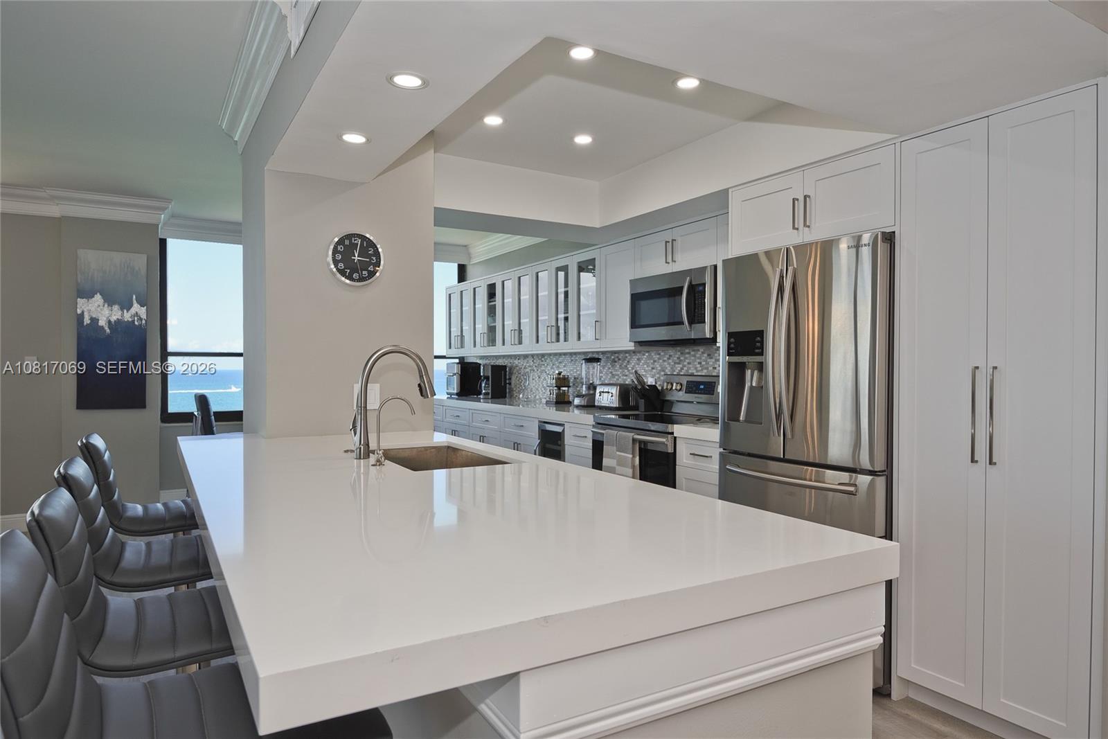 A modern kitchen features white cabinetry, a large quartz island, and stainless steel appliances — 3505 S Ocean Dr # 12, Hollywood FL 33019, HOLLYWOOD, FL
