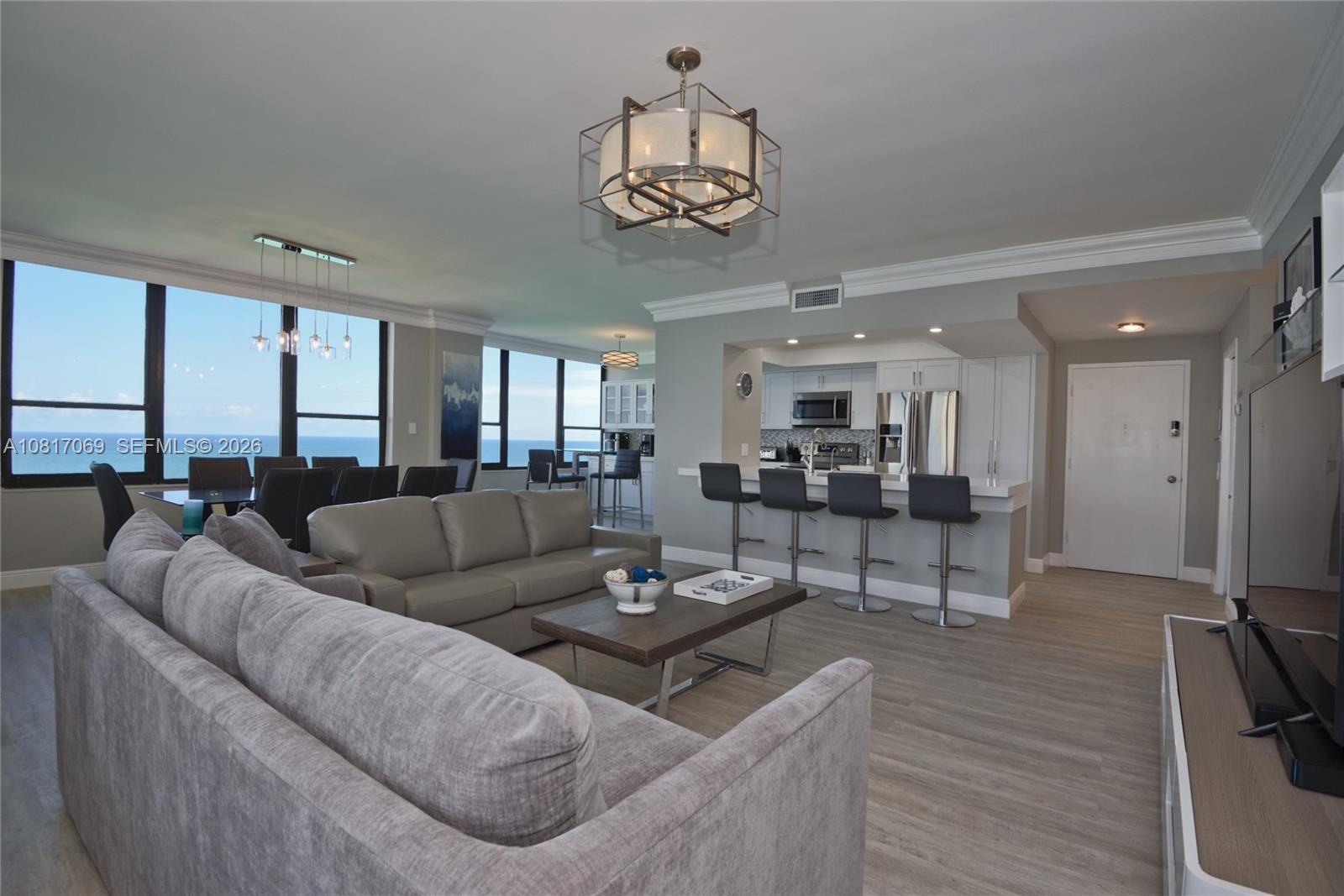 An open-concept living and dining area features a kitchen island, ocean views, and neutral decor — 3505 S Ocean Dr # 12, Hollywood FL 33019, HOLLYWOOD, FL
