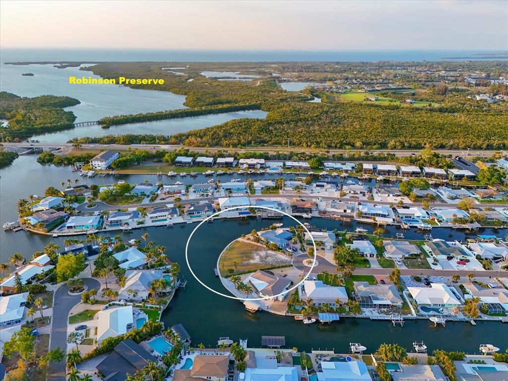 An aerial view shows a waterfront residential peninsula with two houses and a vacant lot — 10412 KINGFISHER ROAD W, BRADENTON, FL