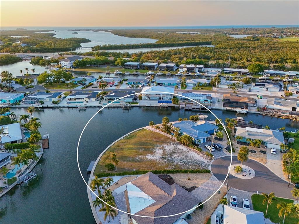 An aerial view shows a vacant waterfront lot situated between two houses on a canal — 10412 KINGFISHER ROAD W, BRADENTON, FL