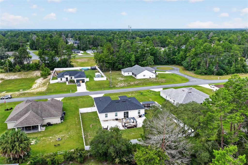 An aerial view shows several single-family homes with yards surrounded by dense forest — 149 MARION OAKS GOLF ROAD, OCALA, FL