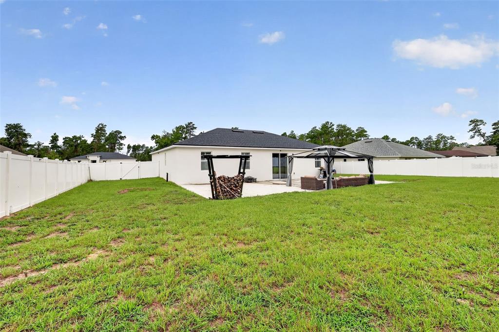 The backyard features a white vinyl fence, a concrete patio, a wood rack, and a gazebo — 149 MARION OAKS GOLF ROAD, OCALA, FL
