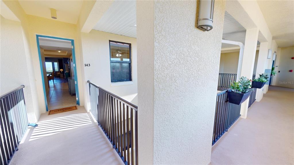 An outdoor walkway leads to the entrance of a residential unit numbered 143 — 1340 ROCK DOVE COURT UNIT 143, PUNTA GORDA, FL